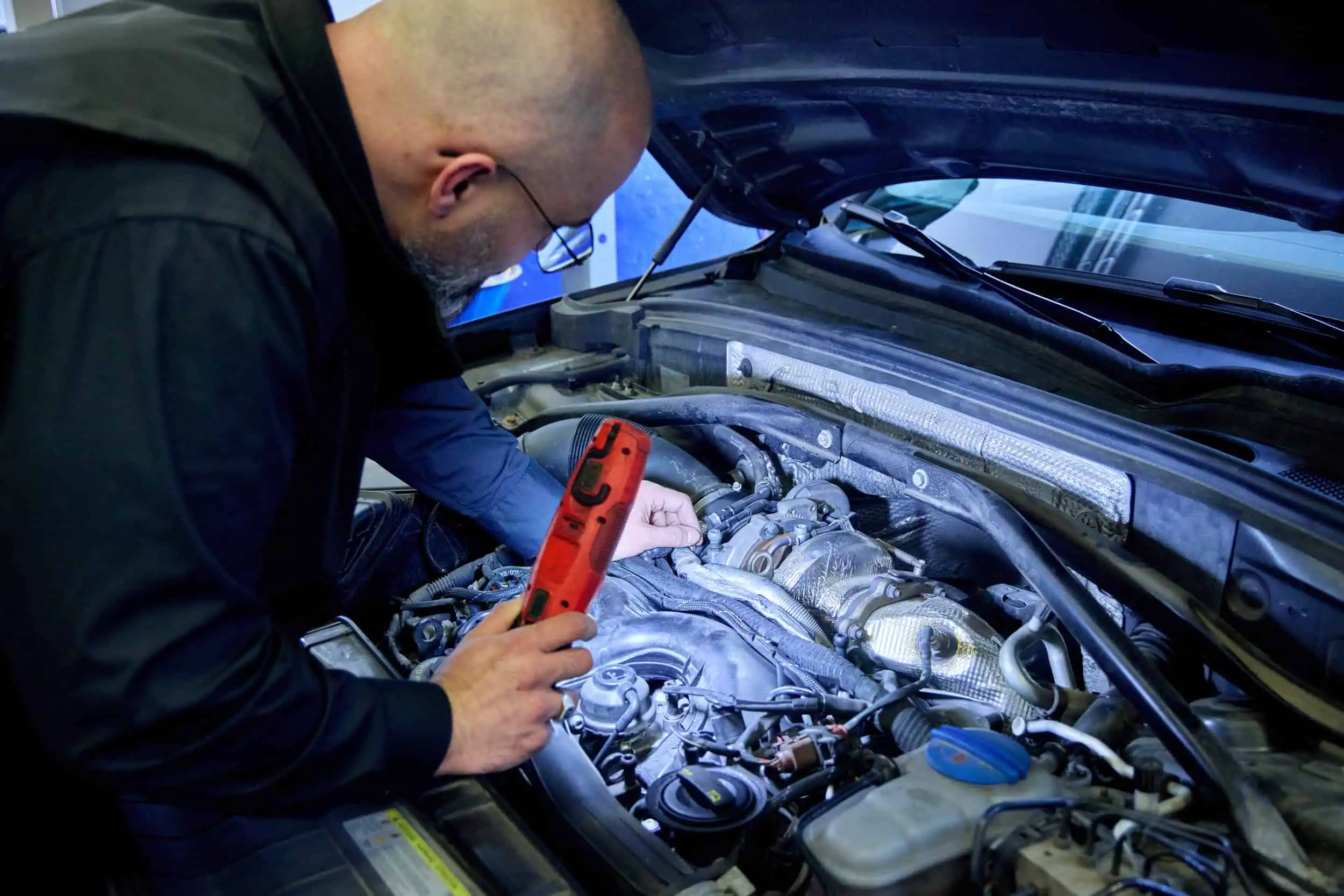 KFZ-Sachverständiger Cengis Atlas bei der gründlichen Begutachtung eines Motorraums