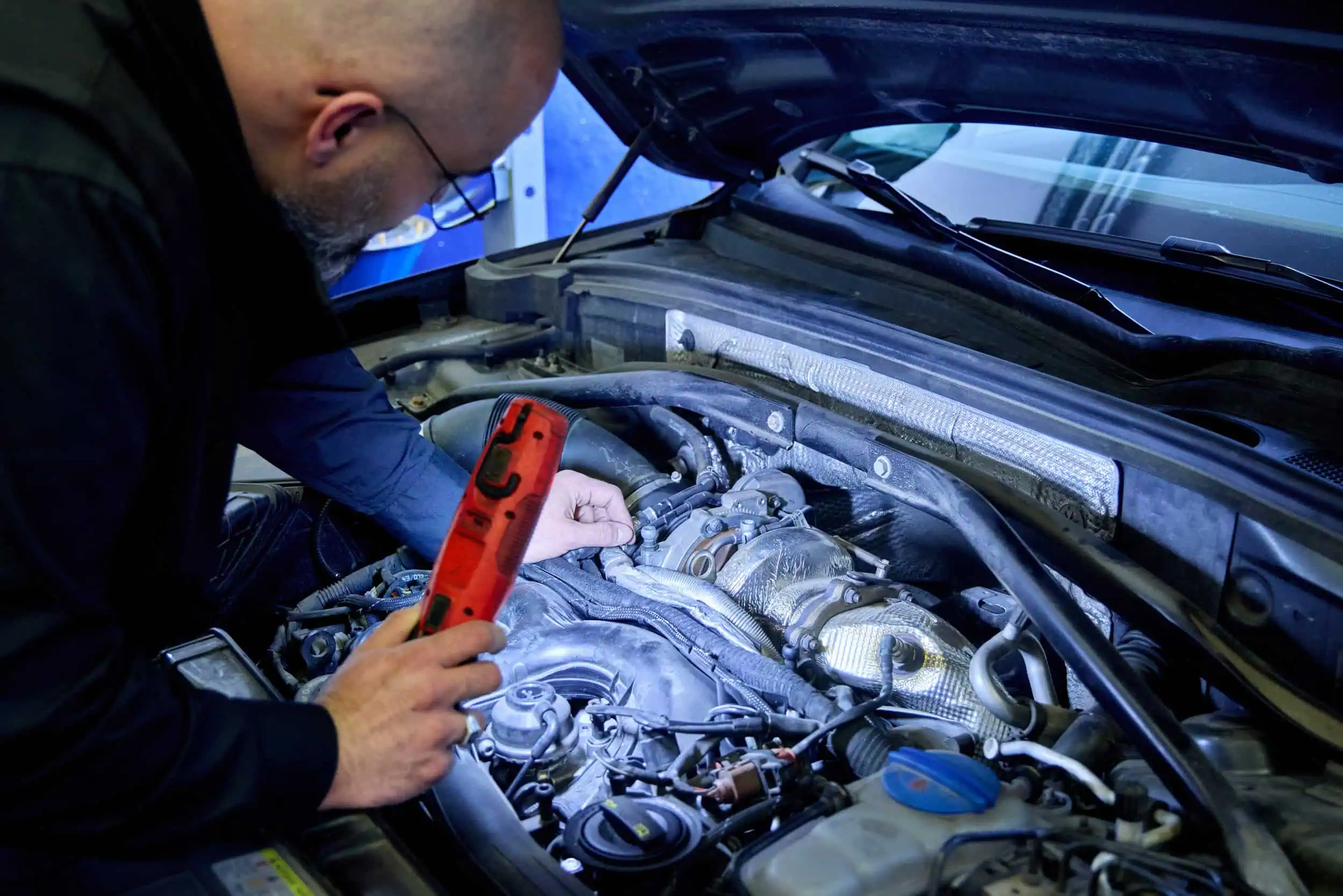 Sachverständiger leuchtet Motorraum zur Begutachtung aus